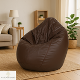 Brown bean bag chair in a living room setting with a lamp, sofa, and plants.